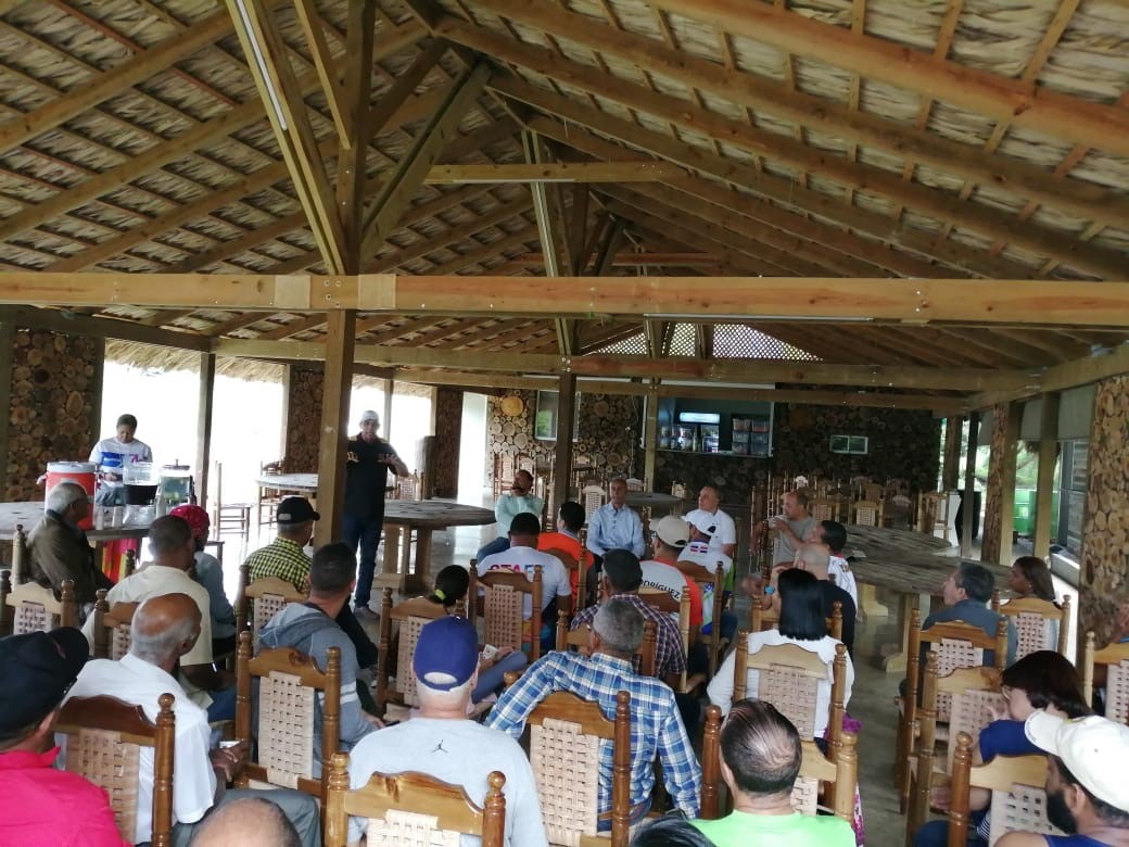 Con una entusiasta participación se realizó este domingo su primera reunión explicativa del Club de Caminantes del Jardín Botánico de Santiago, para dar a conocer los objetivos y alcances del proyecto. Decenas de representantes de los llamados “Clubes de Runners”, Organizaciones Comunitarias y Juntas de Vecinos se dieron cita en el “Café Sinfín” del Parque Botánico, donde intercambiaron con representantes del Consejo que rige la entidad. los pormenores sobre el funcionamiento, compromisos y beneficios de pertenecer a este club de voluntarios. Según explicaron los directivos del Jardín Botánico, el principal motivo para regular el acceso a los senderos del Jardín es la seguridad, debido a que muchos caminantes inician su jornada desde las cinco de la madrugada y para ello es necesario garantizarle condiciones apropiadas, por lo que los vigilantes requerirán que todos los que visiten a esa hora estén identificados y registrados como miembros del Club. Entre los beneficios adicionales están la autorización de ingreso antes y después del horario de uso público, descuento en los alquileres de espacios, actividades exclusivas para miembros del club, entre otros incentivos. Al hablar en nombre de las comunidades de Runners De Santiago, los Sres. Amaury Lora, Alex Moronta, Mario Pérez y Ramón Rodríguez valoraron lo acertada de la medida y pidieron a los presentes “dar un paso más allá” mediante la celebración de al menos un evento anual con todos los clubes y caminantes en apoyo al Jardín Botánico. Em tanto que en nombre del Consejo que administra el Jardín, el Sr. Nelson Bautista aclaró que el acceso al Parque en horario regular de 8 a 5 de la tarde sigue siendo gratuito y que por razones de sostenibilidad sólo se cobran cuotas de alquiler de espacios como la cafetería o los gazebos, así como también a los fotógrafos profesionales que usan los jardines con fines comerciales. “Este es y debe seguir siendo un espacio donde cada uno de los ciudadanos de este país se sienta dueño, parte de el” dijo Bautista, al declarar que para lograr mejores estándares de satisfacción entre los visitantes hace falta mantener las normas de comportamiento, limpieza y seguridad y por ello las reglas de acceso deben acatarse. Durante el encuentro, se entregó el Carnet de Caminante 001 al señor Esteban Cruz, quien fue el primero en registrarse y acogerse a la medida. Al recibir su carnet el Sr. Cruz declaró estar muy complacido con las condiciones y el trato recibido en el Jardín durante el tiempo que ha estado visitándolo cada día y exhortó a los presentes a convertirse como en “guardianes por la preservación de este importante pulmón, no sólo pagando esta pequeña cuota de mil pesos por año, sino aportando de otras formas a cuidar esto que es de todos”. En la actividad se dieron cita directivos de las Juntas de Vecinos de la Urbanización Real, Los Reyes II y III, 12 dirigentes de clubes de runners, el párroco Juan Rodríguez, así como decenas de caminantes habituales del Jardín.