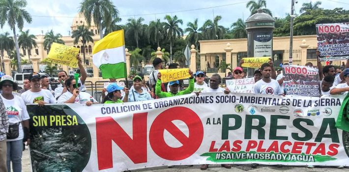 Santo Domingo, DN. - En una manifestación sin precedentes, cientos de serranos se congregaron frente al Palacio Nacional para manifestar su rechazo al proyecto de construcción de la presa de Las Placetas, exigiendo al presidente Luis Abinader que desista de su realización. Esta iniciativa, de llevarse a cabo, tendría consecuencias desastrosas, ya que secaría los ríos Jagua y Bao, fuentes vitales de agua en la región. Los serranos, organizados en la Coalición Socioambiental en defensa de La Sierra y respaldados por la Red Socioambiental Nacional, la Coordinadora Popular Nacional y otras organizaciones de diferentes puntos del país, denunciaron enérgicamente los daños al medio ambiente que ocurren ante la mirada indiferente de las autoridades, y en muchos casos, con la complicidad del Ministerio de Medio Ambiente. Durante la concentración, los manifestantes leyeron un manifiesto que le se exige al gobierno la cancelación del proyecto de la presa de Las Placetas, así como de otras obras que están generando una calamidad ambiental en el país y que desista del intento de privatizar el agua. El llamado se hizo de forma oportuna, previo al Día Internacional del Medio Ambiente, que se celebra este lunes 5 de junio. La presa de Las Placetas ha generado un gran rechazo desde su anuncio inicial en el 2007. Los opositores al proyecto argumentan que la construcción de la presa provocaría la desaparición de los ríos Jagua y Bao, lo que tendría un impacto devastador en el ecosistema local y en las comunidades que dependen de estas fuentes de agua. “Emplazamos al presidente Luis Abinader, al conjunto del Gobierno y la élite financiera y empresarial a que en el curso de este mes de junio respondan las demandas y propuestas de las comunidades y sectores movilizados por sus derechos hoy desplegados aquí frente al Palacio Nacional”. Dijo Llaniris Espinal activista de la Coalición Socioambiental de La Sierra y la Fundación Ecológica Tropical (FUNDETROP). La manifestación también contó con la presencia de destacadas figuras del activismo medioambiental nacional, quienes expresaron su apoyo a los serranos y resaltaron la urgencia de tomar medidas concretas para evitar la destrucción de los recursos naturales del país. Hasta el momento, el gobierno no ha emitido una respuesta oficial ante las demandas de los manifestantes. Sin embargo, la presión ejercida por los serranos y las organizaciones ambientales ha generado un intenso debate público sobre la necesidad de proteger el medio ambiente y tomar decisiones responsables en relación con el desarrollo de proyectos que afecten los recursos naturales. La lucha de los serranos contra la presa de Las Placetas se empodera aun más llegando hasta el Palacio Nacional, recordando a todos la importancia de preservar los ríos Jagua y Bao, y proteger el entorno natural para las generaciones presentes y futuras.